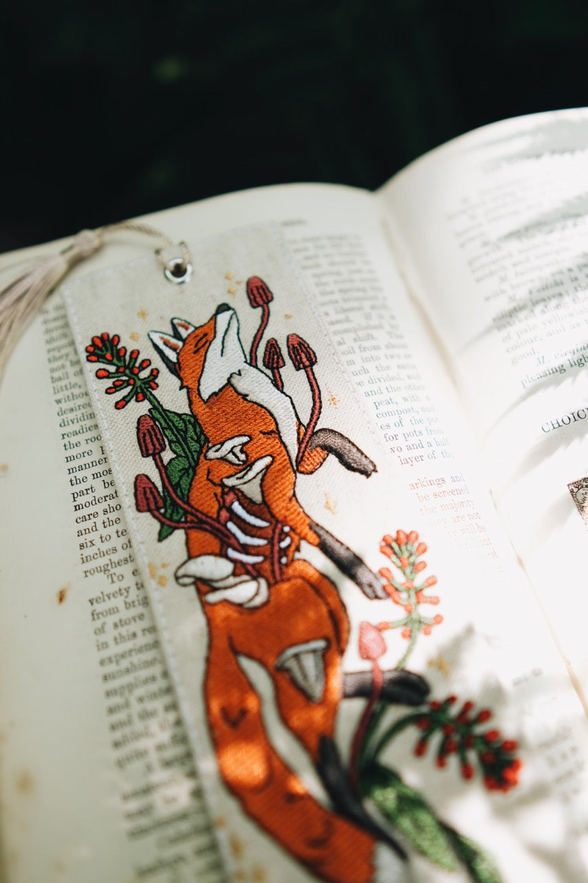 Embroidered design of a fox with flowers on an open book