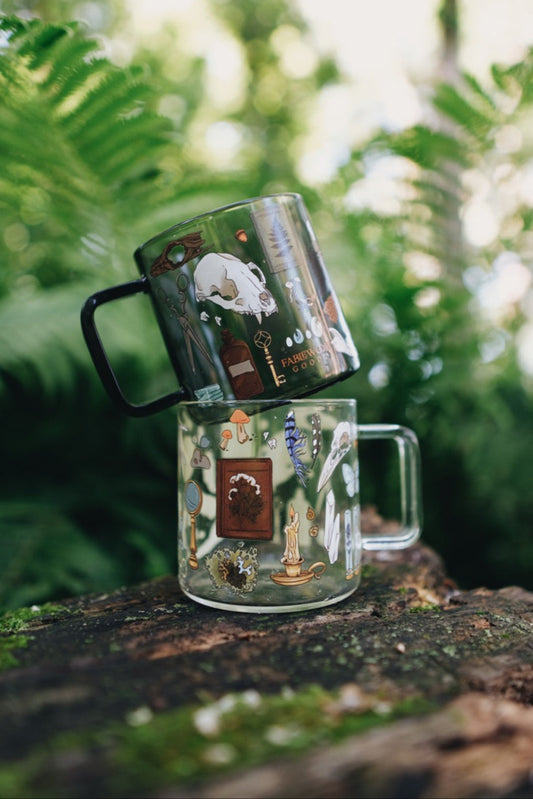Two mugs with artistic designs on a wooden surface with a natural background
